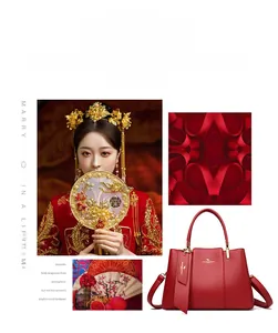 Macro view of red leather wedding handbag with gold logo and adjustable shoulder strap