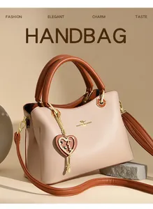 Detail der Lederhandtasche mit goldenem Logo, Herzanhänger und Kontrastnähten