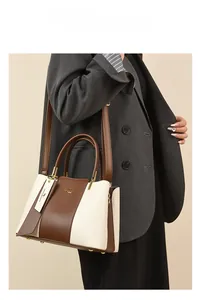 Detail of a vintage contrast color leather handbag with gold rivets and detachable strap