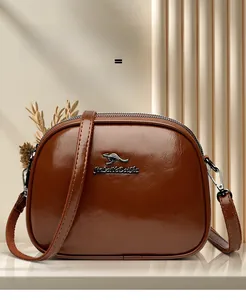 Detailed view of brown oil wax leather crossbody bag with dual zippers and gold hardware