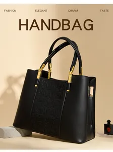 Detailed view of black leather handbag with floral embossing and golden hardware accents