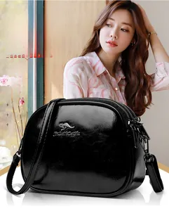 Detail of high-gloss black crossbody bag featuring three-layer zipper and kangaroo logo
