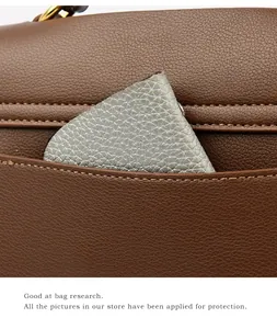 Dettaglio di borsa in pelle marrone con fibbia dorata e tasca laterale esterna