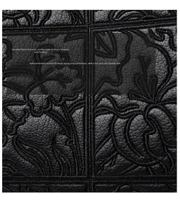 Close-up of black litchi grain leather with elegant floral embroidery detail