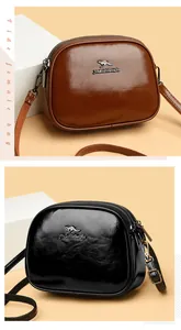 Detail view of double zippers and gold kangaroo logo on oily leather crossbody bags