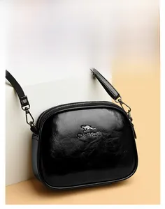 Detailed view of black oil-wax leather texture and polished gold kangaroo logo on crossbody bag