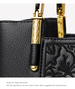 Macro detail of black pebble leather handbag with floral embroidery and golden hardware