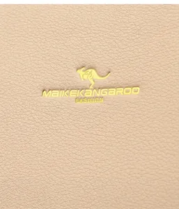 Makroaufnahme der beigen Lederstruktur mit goldenem Känguru-Metalllogo auf der Tasche
