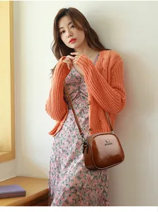 Brown oil wax leather shell-shaped crossbody bag shown on model with floral skirt