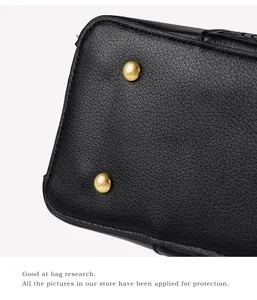 Close-up of black litchi grain leather bag base with protective gold metal feet studs