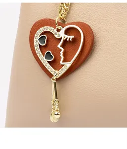 Detail eines Herz-Lederanhängers mit goldener Silhouette und Strass auf einer Handtasche
