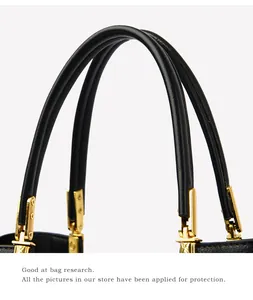 Macro detail of black leather handles with textured gold metal connectors on hand bag