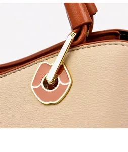 Detail der beigen Lederhandtasche mit goldener lippenförmiger Schließe und Emaille-Akzent