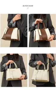 Detail showing two-tone leather tote bag with gold logo and protective metal feet