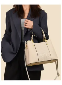 Detail of cream white tote bag with embossed floral pattern held by professional model
