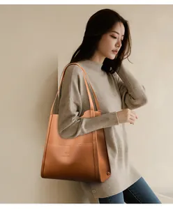 Detailed close-up of orange lychee leather tote bag with embossed kangaroo logo