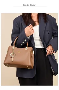 Detail einer braunen Lederhandtasche mit goldenem Känguru-Logo und Herzanhänger