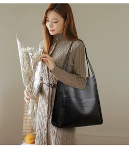 Detail view of large black lychee pattern leather tote bag with front pocket and logo