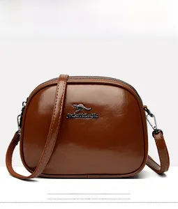 Detailed front view of brown oil wax leather crossbody bag with metal kangaroo logo
