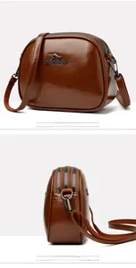 Detail view of brown oil wax leather shoulder bag with triple zipper compartments