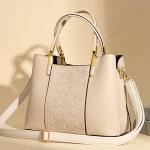 Elegant cream leather handbag with floral embossing and adjustable shoulder strap