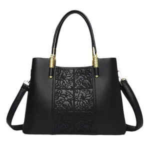 Elegant black leather handbag with embossed floral pattern and gold hardware on white background