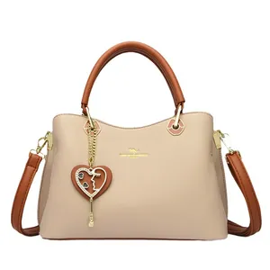 Elegante beige Lederhandtasche mit braunen Riemen und Herz-Anhänger für Damen