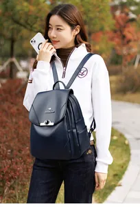 Dettaglio dello zaino in pelle blu navy con logo a canguro e tasche laterali sul modello
