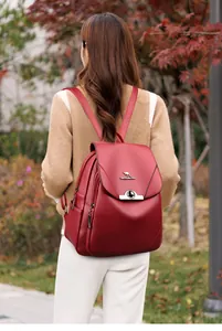 Dettaglio dello zaino in pelle rossa con logo a canguro e patta indossato da una modella