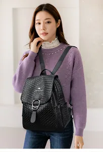 Detail of black faux crocodile leather backpack featuring silver ring and woven shoulder straps