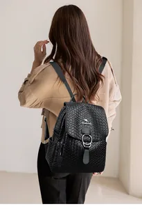 Detail of black faux leather backpack featuring woven texture and silver ring buckle