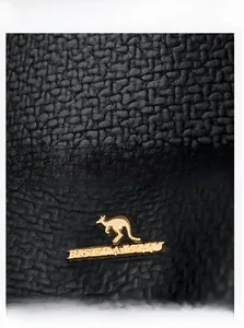 Close-up of black lychee grain leather texture and golden kangaroo metal logo detail