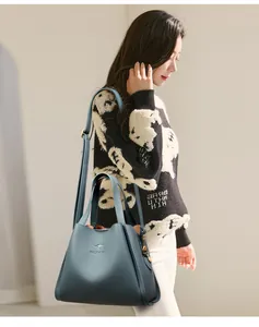 Detail view of blue lychee grain leather tote with golden hardware and brand logo