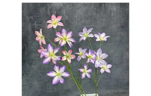 Dettaglio di fiori di clematide artificiale rosa e viola in un vaso quadrato bianco