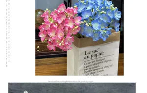 Detailed view of pink and blue artificial jasmine flowers in a paper bag on a wooden table