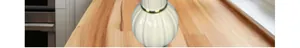 Détail d'un vase en céramique blanche à rayures verticales et anneau métallique doré