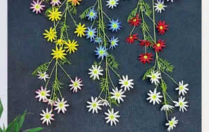 Detail of colorful artificial daisies with vivid petals and green leaves on dark background