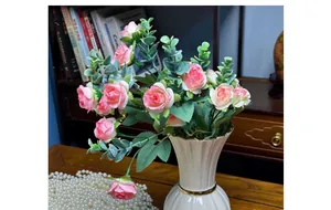 Detailed view of artificial pink roses in a white ceramic vase with gold trim for decor
