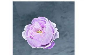 Detail view of purple silk peony flower head with layered petals and yellow stamens