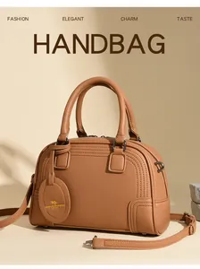 Detailed view of caramel brown leather Boston bag with metal hardware and soft shadow