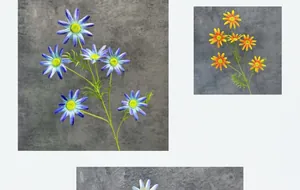 Detailed view of artificial daisy heads in gradient blue and orange with green leaves