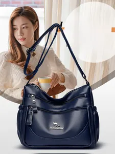 Detail of navy blue pebble leather shoulder bag showing multi-zippered compartments