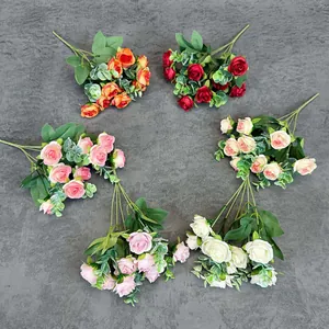 Top view of six colorful artificial rose bouquets with green leaves on gray background
