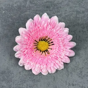 Pink artificial daisy head with yellow stamen on a dark textured background