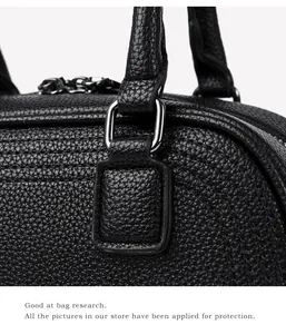 Detail of black pebbled leather texture, silver D-ring hardware and stitching on a tote bag