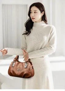 Brown leather handbag with kangaroo metal logo and double handles shown on a model