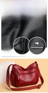 Detail of burgundy textured leather handbag showing multi-layered zippers and logo