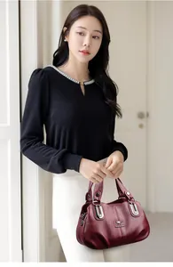 Close-up of wine red leather handbag with silver hardware and embossed brand logo detail