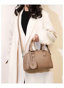 Close-up of brown litchi grain leather Boston bag with double handles and metal hardware