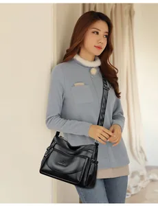 Detail of black leather handbag featuring multiple zipper layers and adjustable strap